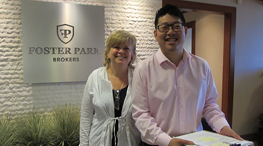 Peter Lee stands in the front lobby of Foster Park Brokers with a colleague