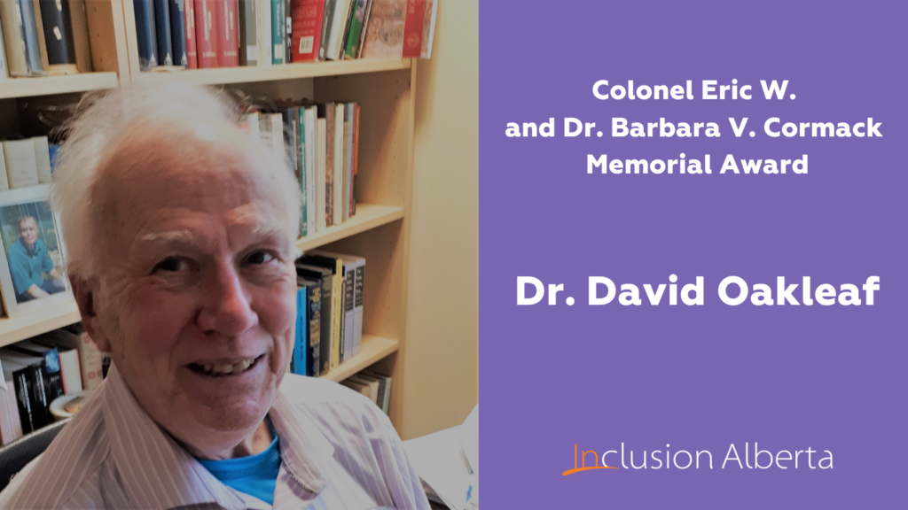 Cormack Memorial Award Winner Dr. David Oakleaf. David poses in front of a books shelf, wearing a beige shirt
